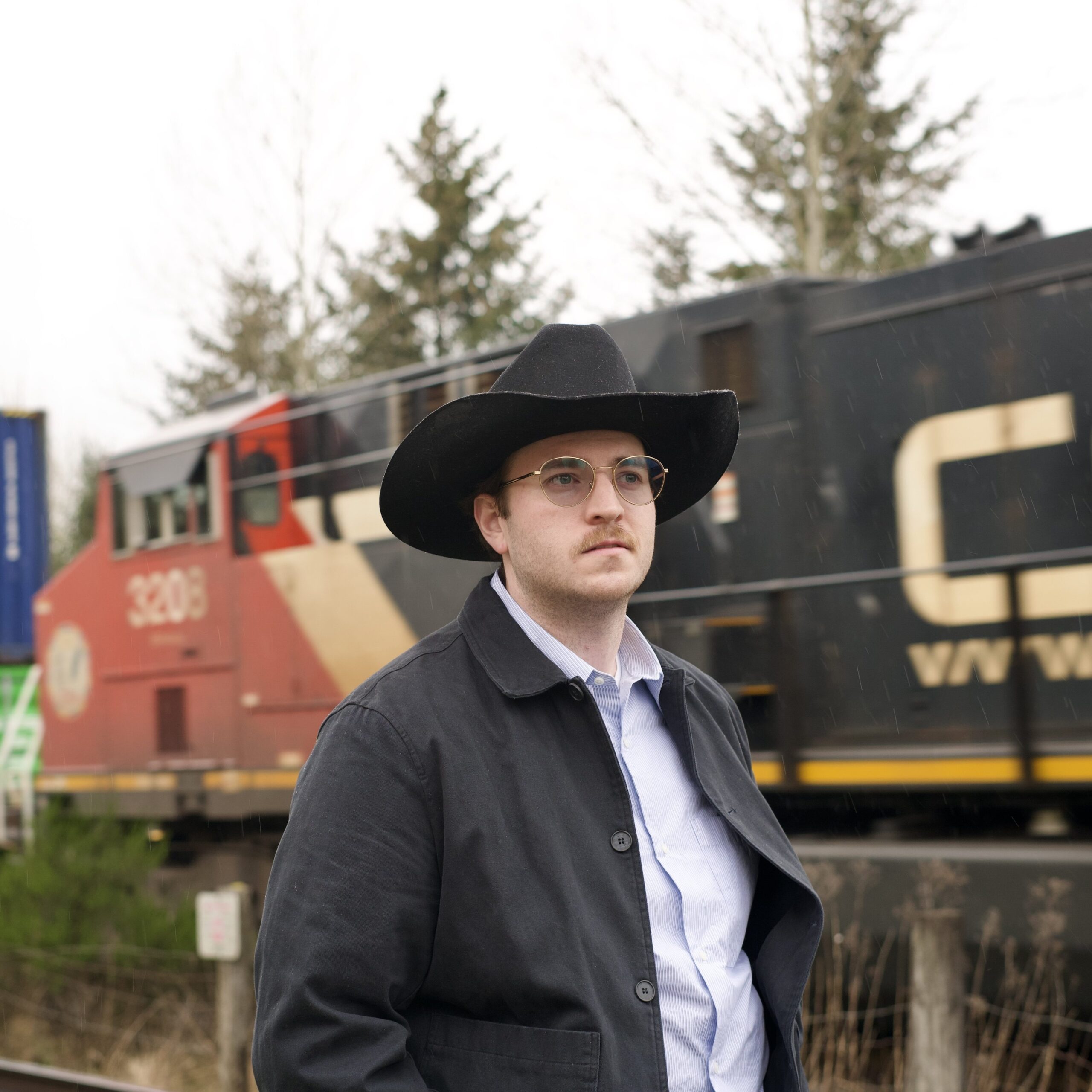 Canadian singer-songwriter Austin T. O'Keefe posing at the historic CN Railway station in Fort Langley, showcasing a blend of traditional country music and Canadian heritage.